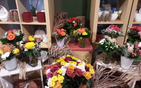 Ein Laden von innen. Verschiedene Blumensträuße stehen auf einer Anrichte. Dahinter stehen bunte Blumentöpfe im Regal.