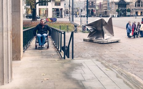 Ein Mann im Rollstuhl fährt die Rampe vor der Kunsthalle Bremen herauf.