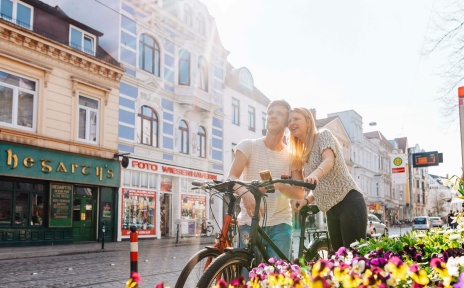 Zwei Personen stehen mit ihren Fahrrädern im Bremer Viertel und gucken sich die Umgebung an.