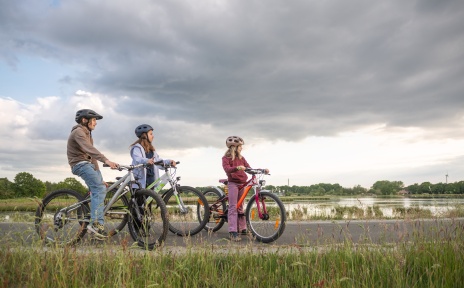 Drei Kinder sitzen auf ihren Fahrrädern in der Natur.