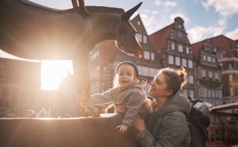 Das Foto zeigt eine Mutter und ihr Kind, wie sie den Esel der Bremer Stadtmusikanten anfassen.