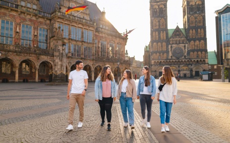 Fünf Personen stehen auf dem Bremer Marktplatz. Im Hintergrund ist das Rathaus und der Bremer Dom zu sehen.
