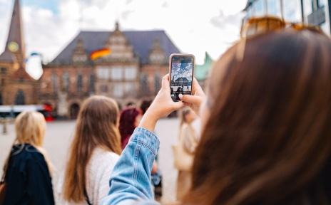 Eine Gruppe läuft über den Bremer Marktplatz. Eine Person macht ein Foto vom Rathaus.