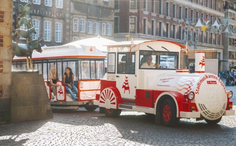 Zwei Frauen fahren im Stadtmusikantenexpress an der Statue der Stadtmusikanten vorbei.