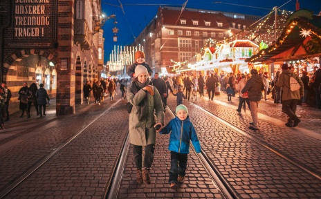 Eine Frau geht mit zwei Kindern auf dem Bremer Weihnachtsmarkt spazieren