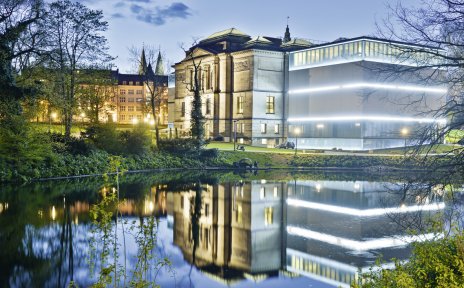Blick auf das die beleuchtete Kunsthalle bei Nacht mit dem historischen Gebäudeteil und dem modernen Anbau