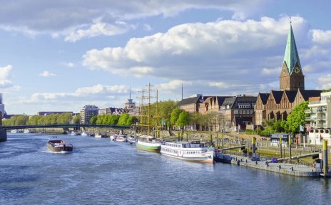 Ein Binnenschiff fährt an der Weserpromenade Schlachte mit ihren vielen Schiffen vorbei.