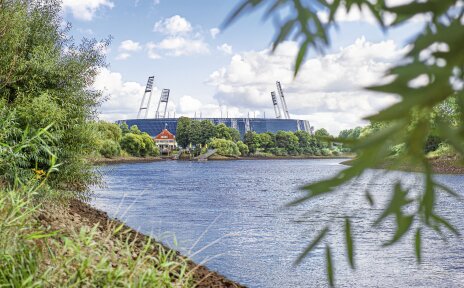 Das Weserstadion an einem Fluss umgeben von grüner Natur.