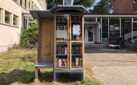 Ein öffentlicher Bücherschrank mit kleiner Sitzgelegenheit. 