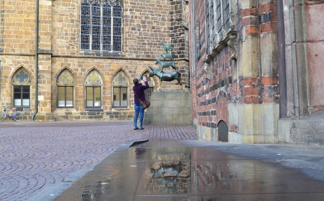 Eine Frau fotografiert die Statue der Bremer Stadtmusikanten an der Westseite des Rathauses.