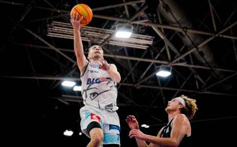 Zwei Basketballer nähern sich mit einem Ball dem Korb. 