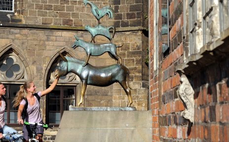 Zwei Fahrradfahrer und die Statue der Bremer Stadtmusikanten