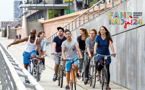 Fahrradfahrer:innen fahren am Wasser entlang. Rechts oben ist das Logo von "FAHRRADja! 2024. Bremen bewegt dich." zu sehen.