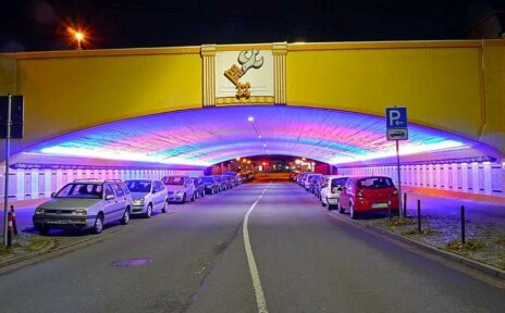 Das Foto bildet die Frontseite des Tunnels zum Stern hin ab inklusive Taube-Schlüssel Emblem bei Nacht. Der Tunnel wird in Regenbogenfarben erstrahlt.