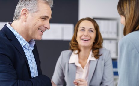 Zwei Frauen und ein Mann lachend in einem Geschäftsgespräch (Quelle: fotolia / contrastwerkstatt)