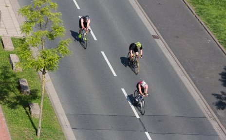 Triathlon-Teilnehmer fahren auf Fahrrädern über die Straße.