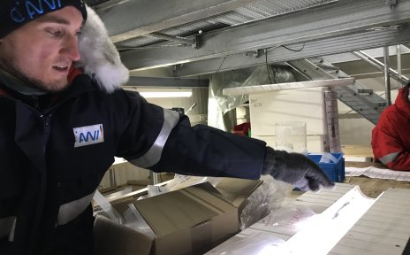 Ein Mann in Winterkleidung vor einer leuchtenden Röhre mit Eis