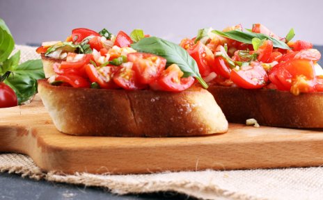 Bruschetta: geröstete Brotscheiben mit Tomate und Basilikum auf einem Holzbrett