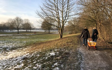 Zwei Frauen ziehen einen Bollerwagen durch eine winterliche Landschaft