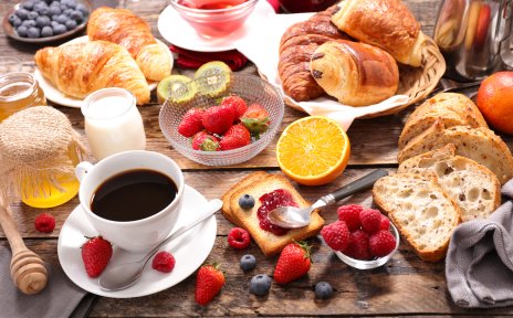 Ein großes leckeres Frühstück mit Kaffee, Croissant und verschiedenen Obstsorten.