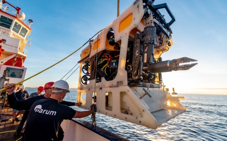 Eine Maschine wird von MARUM-Mitarbeitern auf einem Schiff ins Meer gelassen.