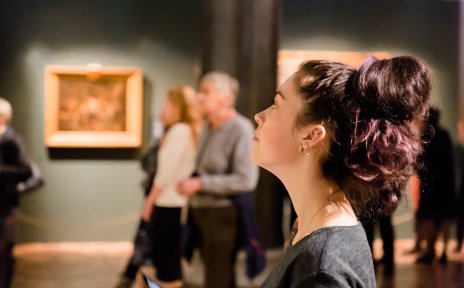 Eine Frau betrachtet ein Gemälde in einer Museumsausstellung.