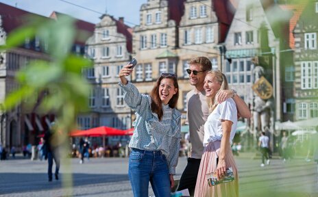 drei Personen stehen auf dem Bremer Marktplatz und machen ein Selfie