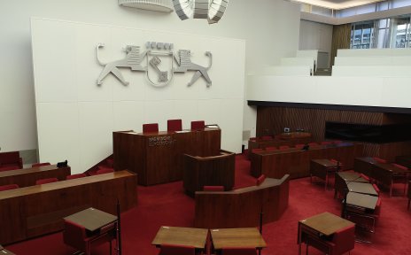 Ein großer Saal in der Bremischen Bürgerschaft mit Holzpult, rotem Teppich, Holztischen und roten Stühlen. 