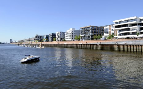 Blick auf den Europahafen, im Vordergrund ein kleines Motorboot auf der Weser, im Hintergrund Büro- und Wohngebäude.