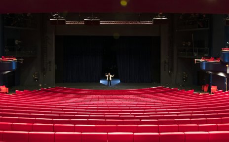 Ein großer Theatersaal mit roten Sitzreihen.