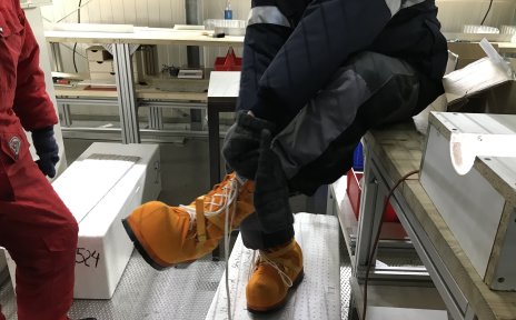 Ein Mann mit dicken gelben Schuhen und Winterbekleidung in einem Labor