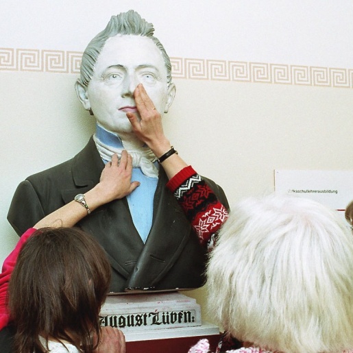 Menschen ertasten eine Skulptur in einer Ausstellung.