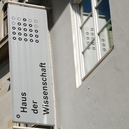 Eine Fahne mit der Aufschrift "Haus der Wissenschaft" hängt an der Außenfassade.