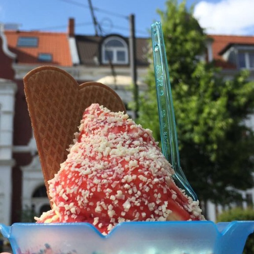 Ein Spaghetti Eis mit einer Waffel in einem blauen Becher wird in der Wachmannstraße bei Eis Molin hochgehoben.