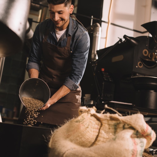 Ein Arbeiter schüttet Kaffeebohnen in eine Maschine