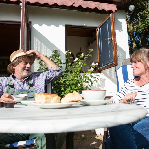 Ein Mann und eine Frau sitzen an einem Gartentisch und lachen sich zu; Quelle: WFB/Jens Lemkühler