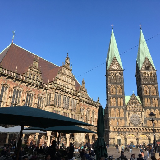 Das Bremer Rathaus und der Bremer Dom und der Marktplatz, auf dem Leute in einem Café sitzen 