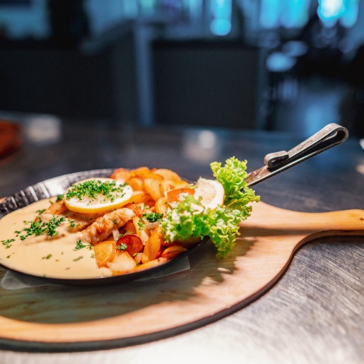 Eine gusseiserne kleine Pfanne, in dem ein Fischgericht serviert wird.