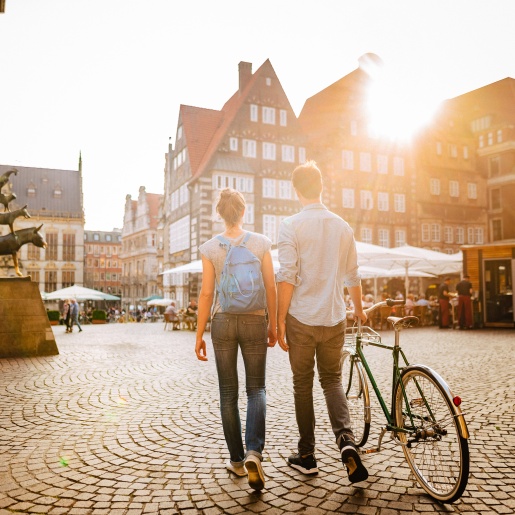 Ein Pärchen mit einem Fahrrad läuft bei den Bremer Stadtmusikanten lang