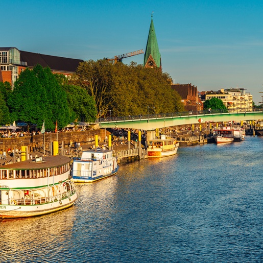 Blick auf Schiffe, schlendernde Menschen und Biergärten an der abendlichen Weserpromenade Schlachte 