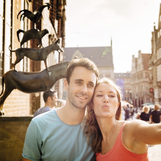 A couple takes a selfie in front of the Bremen Town Musicians.