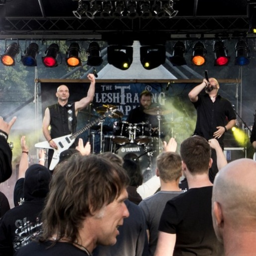 Metal Fans stehen vor einer Bühne und feiern. 