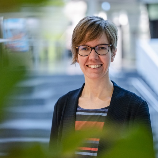 Portrait von einer Frau, die vor einer Treppe steht und lacht