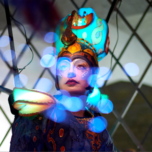 Close-up of a person wearing make-up and a brightly coloured headdress.