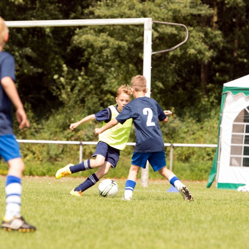 Drei Jungs spielen Fußball auf einem Rasenplatz