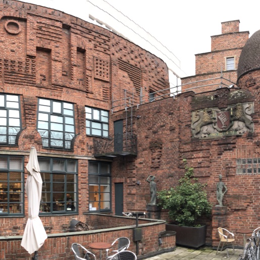 Die rotbraune Außenfassade der Museen Böttcherstraße mit Terrasse und Kuppel. Auf der rechten Bildseite ist ein kleiner Teil der Gasse "Böttcherstraße" zu erkennen.