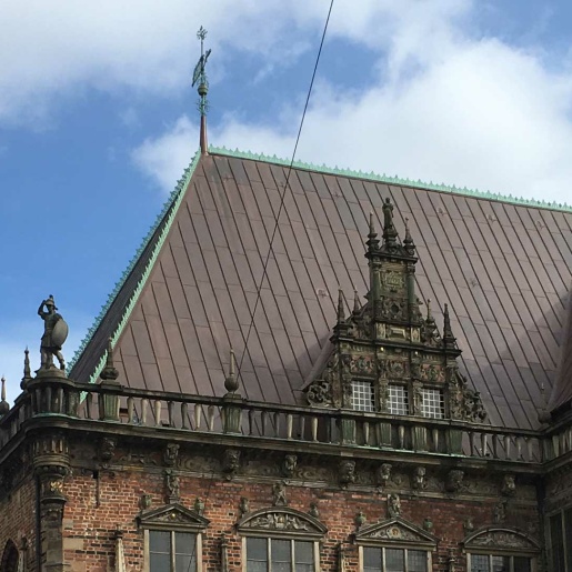 Das kupferfarbene Dach des Rathauses vor blauem Himmel