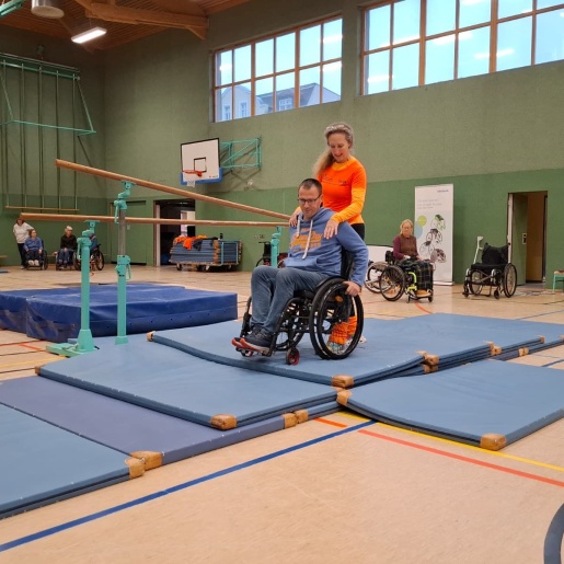 Menschen beim Rollstuhl-Training in einer Sporthalle.