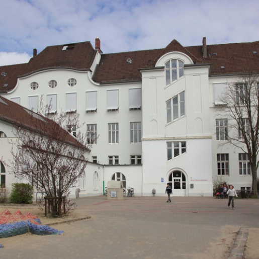 Weißes Gebäude des Schulmuseums mit Kindern davor.