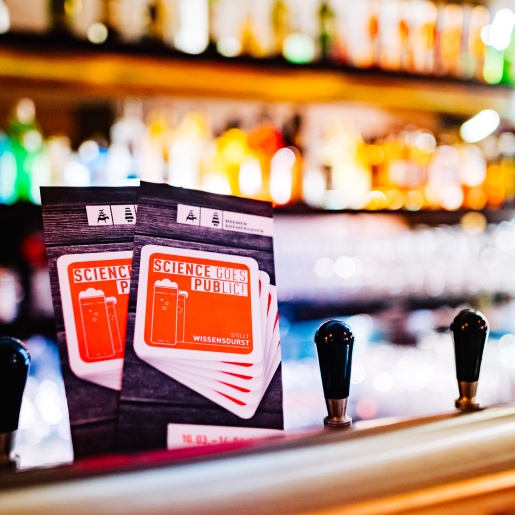 Flyer SCIENCEE GOES PUBLIC! auf dem Zapfhahn in einer Kneipe